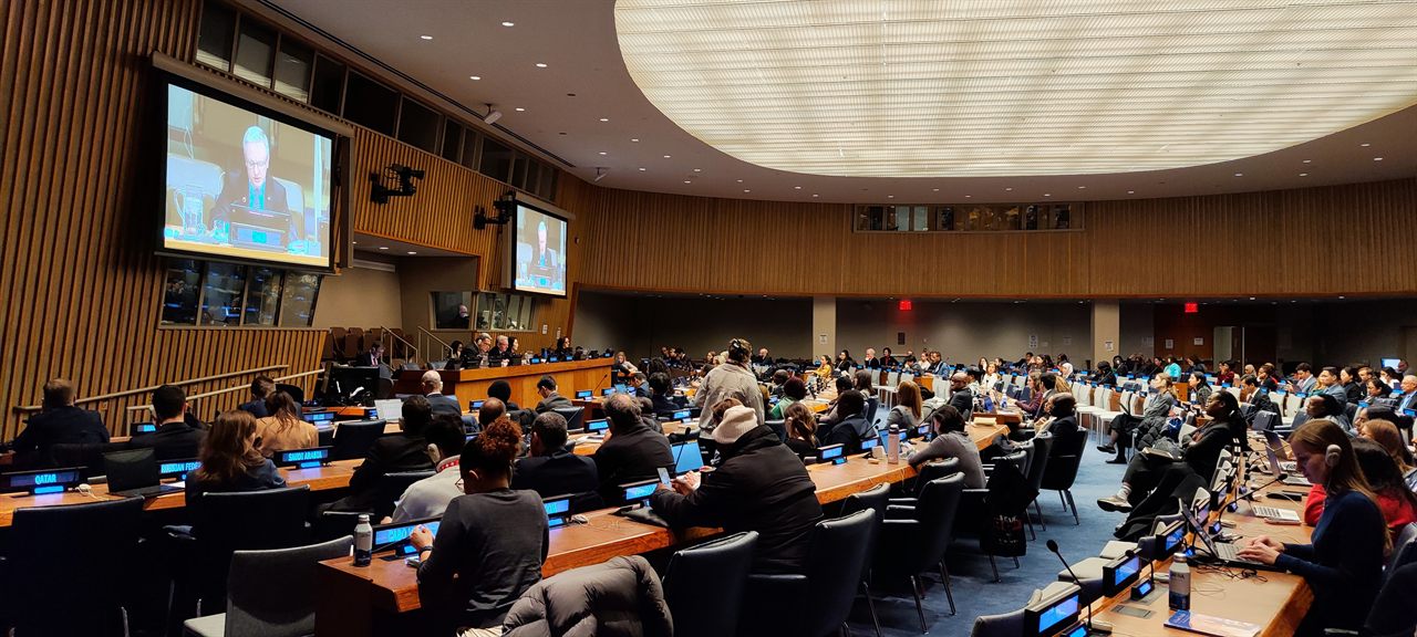 Delegates seated at desks with country nameplates during a UN committee session in New York